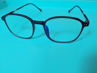 A pair of black-framed glasses casts a shadow on a white surface.