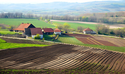 A scenic view of cultivated fields and rustic houses in a rural landscape.