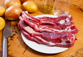 Raw beef ribs on the kitchen table along with other ingredients for making a delicious lunch or dinner