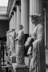 Antique statues of Women in Wreaths. The white stone statues stand in a neat row among Greek-style columns