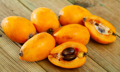 Fresh nispero or japanese medlar fruit whole and cutted on wooden table