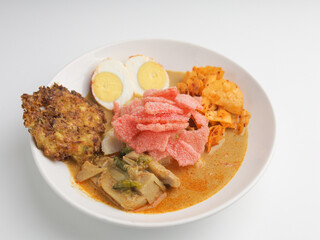Homemade rice cake or Lontong Sayur, cooked with vegetable curry and served with boiled egg, fritter, and crackers on white plate