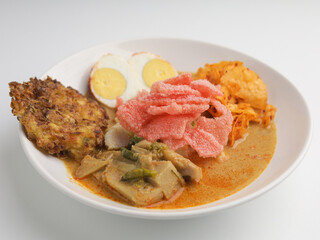 Homemade rice cake or Lontong Sayur, cooked with vegetable curry and served with boiled egg, fritter, and crackers on white plate