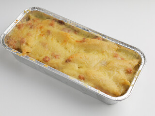 Homemade baked macaroni and cheese in aluminum foil on white background