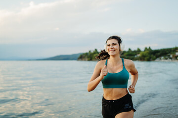 Young woman running or jogging on the beach at sunset	