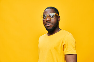 Portrait of a young man wearing yellow glasses and a matching shirt against a vibrant yellow background, exuding confidence and style, perfect for fashion and lifestyle themes