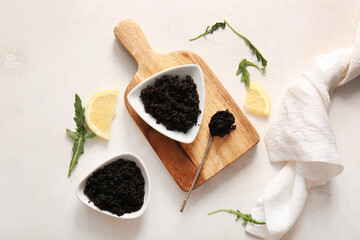 Bowls with delicious black caviar, arugula and slices of lemon on white background