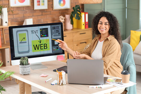 Female African-American web designer working with computer at table in office