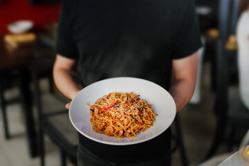 The waiter serves an Asian aromatic dish of noodles, vegetables and chicken. Traditional Vietnamese cuisine.