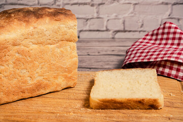 White bread loaf on a cutting board next to a freshly cut slice.