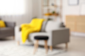 Modern interior of living room with stylish sofa and yellow plaid, blurred view