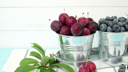 Plums, red currants and blueberries in small metal bucket