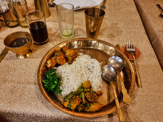 A traditional newari meal consisting of rice,vegetables,lentils and a meat dish served on copper plates in a traditional dining restaurant in Kathmandu,Nepal 