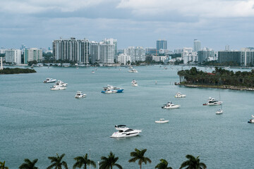 Scenic view of Miami's skyline with boats on the water, under a cloudy sky, showcasing urban architecture and leisure activities.