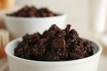 Bowl with coffee body scrub on light grunge background, closeup
