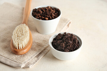 Bowls with coffee body scrub, coffee beans and massage body brush on light grunge background