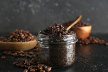 Jar with coffee body scrub on black grunge background, closeup