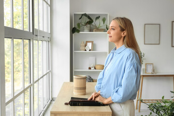 Mature woman with prayer beads and Holy Bible on commode at home