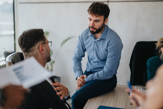 A diverse group of business people engaged in a collaborative meeting. The setting is casual, with people discussing ideas and strategies in a modern office environment.