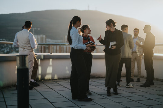 A group of diverse and multiracial business colleagues are engaged in a brainstorming session on a high tower balcony during sunset, fostering creative and collaborative discussions.
