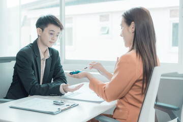 Fototapeta premium The person in question consults the car salesman with the purchase agreement for inspection at the showroom. The customer receives a vehicle purchase contract before signing with the dealer.
