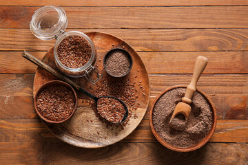 Jar with flax seeds and bowls of flour on wooden background