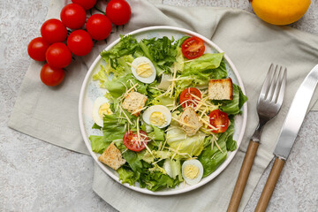Plate with tasty Caesar salad, tomatoes and lemon on grey background
