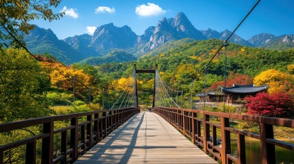 Obraz premium Scenic bridge surrounded by vibrant autumn foliage and majestic mountains.