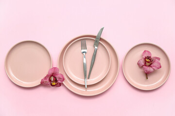 Stylish table setting with beautiful orchid flowers on pink background