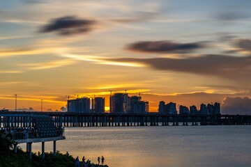 Fototapeta premium Crowds gather to enjoy a vibrant summer sunset at Qianhai Bay in Nanshan District, Shenzhen