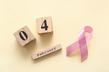 Pink awareness ribbon and cube calendar with date of World Cancer Day on beige background