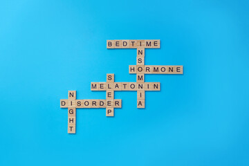 Word melatonin and other words left in the crossword on the topic of insomnia on blue background. Conceptual banner on the topic of insomnia. Selective focus, copy space