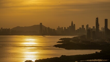 Fototapeta premium Shenzhen Bay Park at sunset with cityscape reflecting golden hues on the water