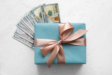 Beautiful Christmas gift and dollar banknotes on light background
