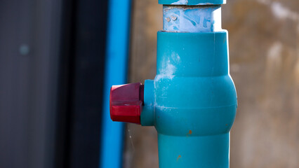 Naklejka premium Blue plastic water pipe attached to the wall of a building with sunlight