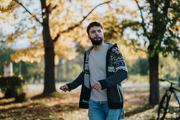 A young man wearing a cozy sweater walks through a vibrant autumn park, surrounded by colorful leaves and sunshine. The serene setting evokes feelings of peace and relaxation.