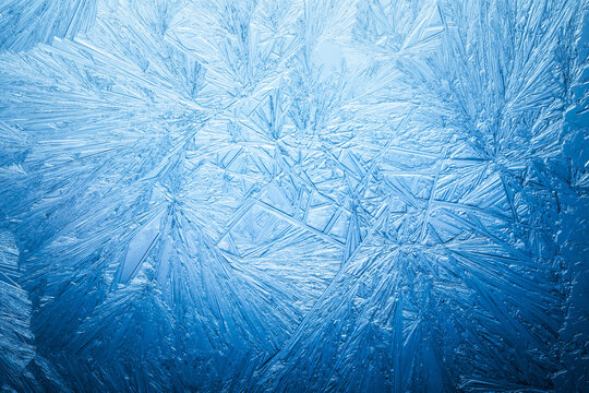 Snowflake frost patterns on glass. Vivid ice crystal textures on clear glass window. Frozen surface, snow flake structure, or freezing cold winter background.