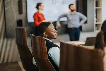 A multicultural business team engaged in a modern meeting, with a focus on a presentation. The environment is collaborative and professional, emphasizing teamwork and communication in a contemporary