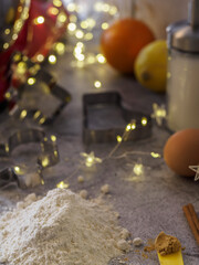 Ingredients to prepare Christmas cookies. Kitchenware and Christmas lights.