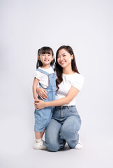Full body image of Asian mother and daughter posing on white background