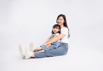 Full body image of Asian mother and daughter posing on white background