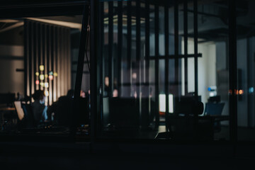 A group of multiracial colleagues collaborate in a softly lit office, discussing projects and strategies at night. The atmosphere suggests focus, teamwork, and meeting tight deadlines.