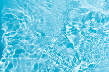 Blue water with ripples on the surface. Defocus blurred transparent blue colored clear calm water surface texture with splashes and bubbles. Water waves with shining pattern texture background.
