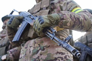 The muzzle of a machine gun. A soldier holds a weapon in his hands.