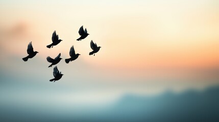 Obraz premium A group of birds in flight, their silhouettes blurred against the backdrop of a cloudy sky, creating a sense of freedom and movement.