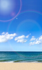 雲一つない南国の透き通った青い空と海と砂浜に光り輝く光のフレア　縦型写真