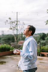 Fototapeta premium A Southeast Asian man enjoying a sip of coffee on a peaceful morning