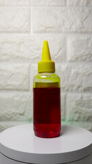 Yellow printer ink in a clear plastic bottle placed against a white background. Ideal for...