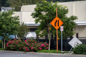 Orange left lane merge sign, Lane Reduction Transition Sign, as a caution in an urban construction...