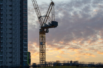 Dec 16 2024,Hong Kong.A series of construction cranes rise against a colorful sunset, casting long shadows over a busy construction site